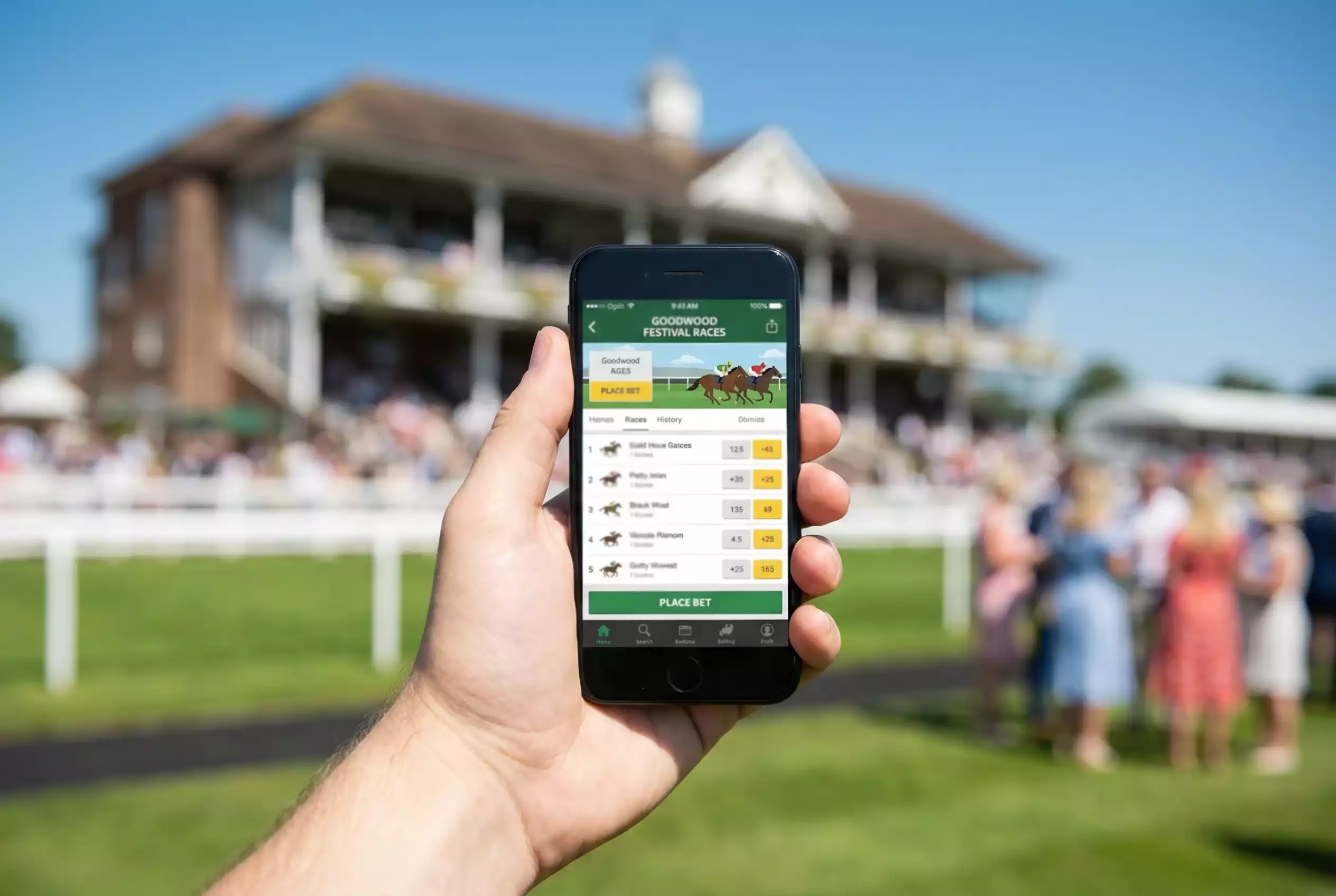 A racegoer using a betting app on a smartphone at Goodwood with the racecourse in the background